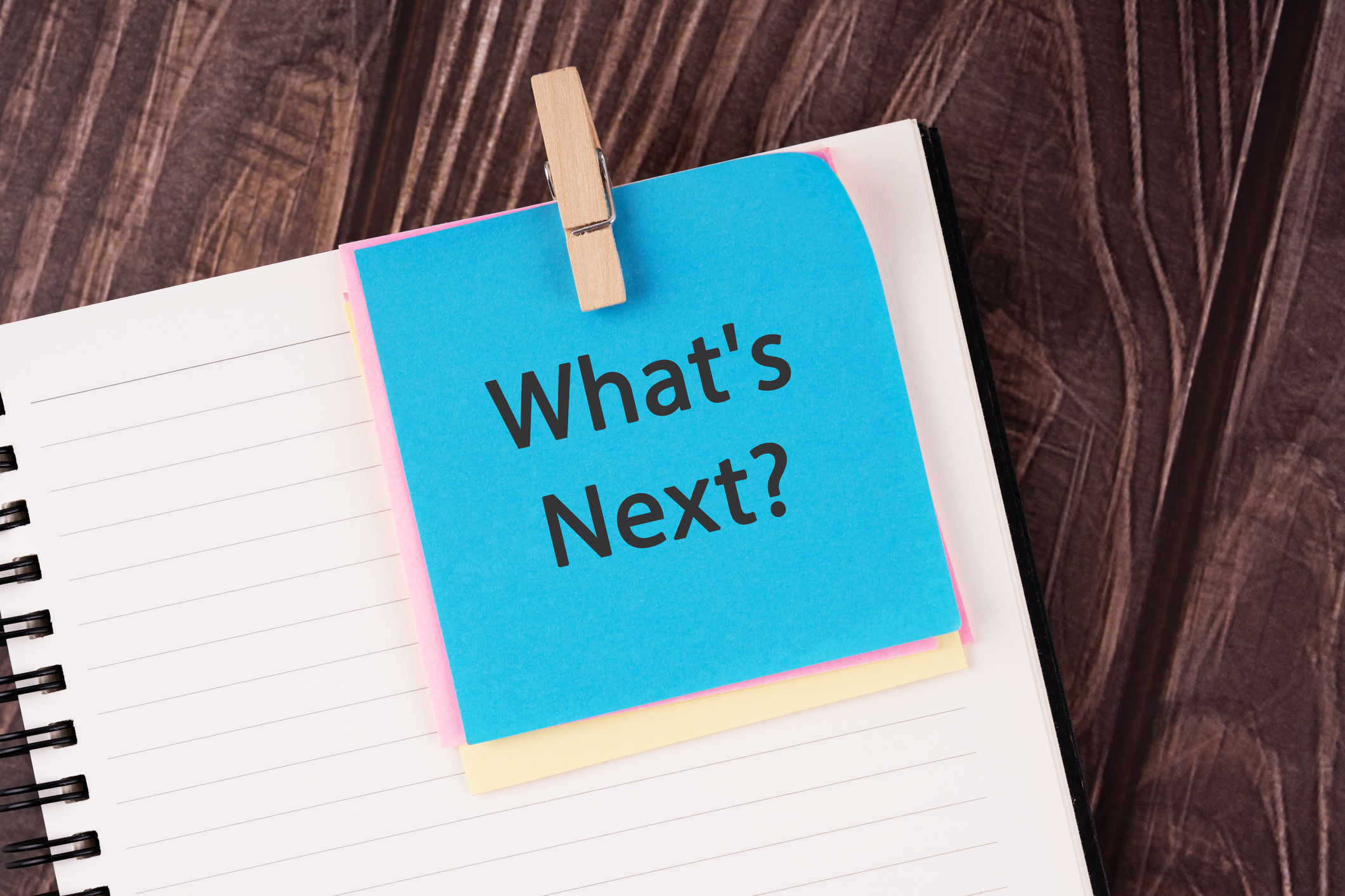 the words &amp;quot;what's next&amp;quot; written on a blue Post-it note and clipped to a notepad