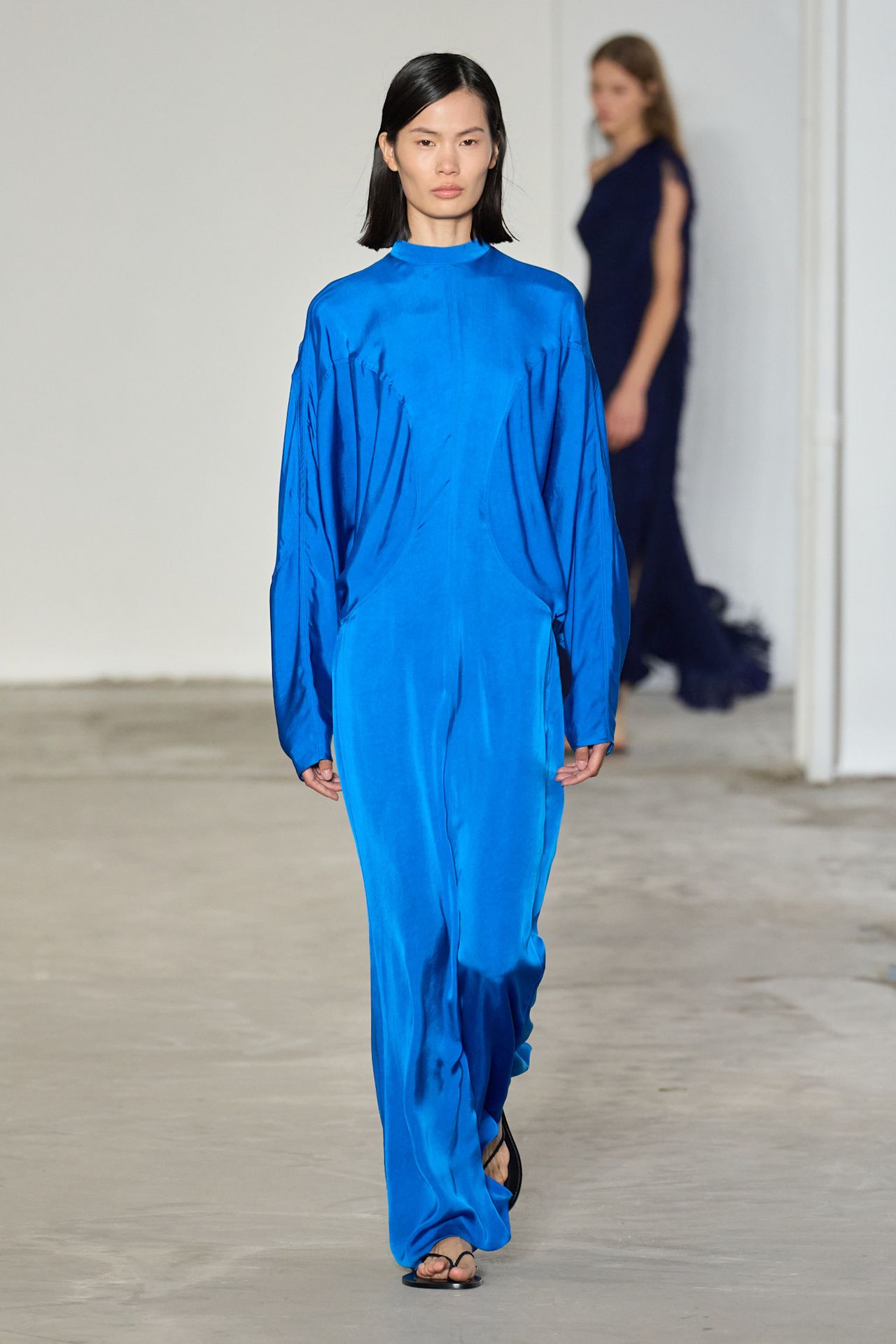 A Fforme model wearing a cobalt blue maxi gown with black flip-flop sandals.