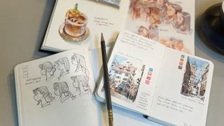 Inside the sketchbook of; artist sketchbooks and art on a table with a pencil