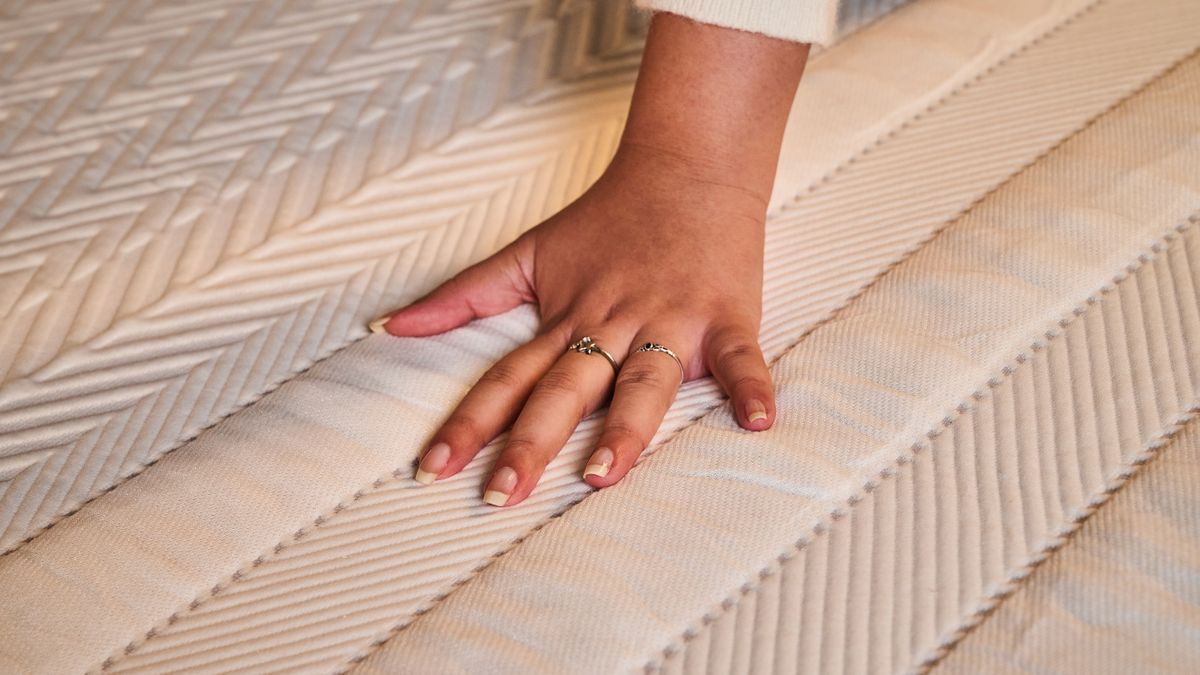 A close-up of a hand feeling the materials of the Leesa Legend Hybrid Mattress 's cover design