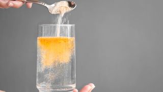 Orange fizzy powder and water glass with copy space