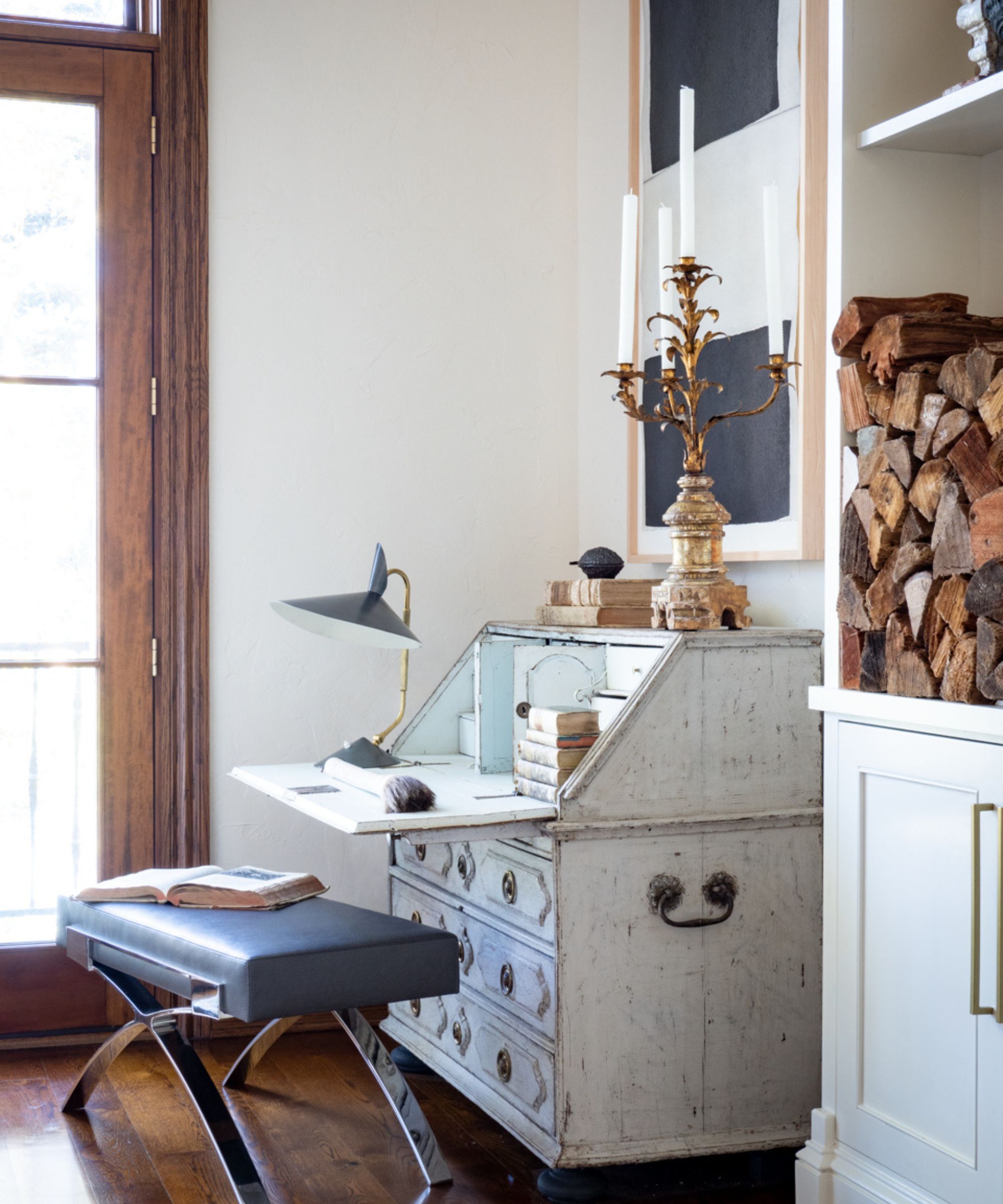Fold out desk and leather stool, ornate gold candelabra and modern painting