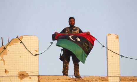 A Libyan rebel holds a Kingdom of Libya flag at Gadhafi&amp;#039;s compound in Tripoli