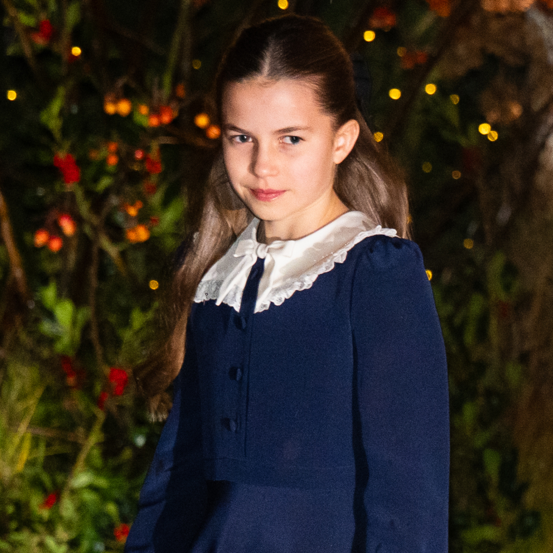 Princess Charlotte in a blue dress in front of a lit tree