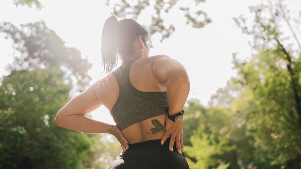 A woman holding her lower back in pain after a run