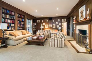 A living room with wood panelled walls, striped sofas, and built-in bookshelves