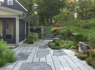 decking with stone wall, lawn and green garden chairs