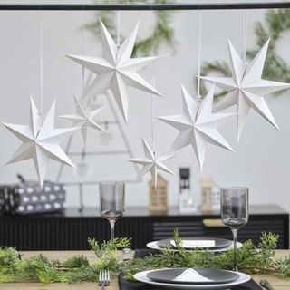 White paper star decorations hanging on a shower curtain pole Christmas decoration trend
