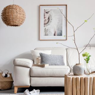 A neutral living room with a wooden coffee table and light shade