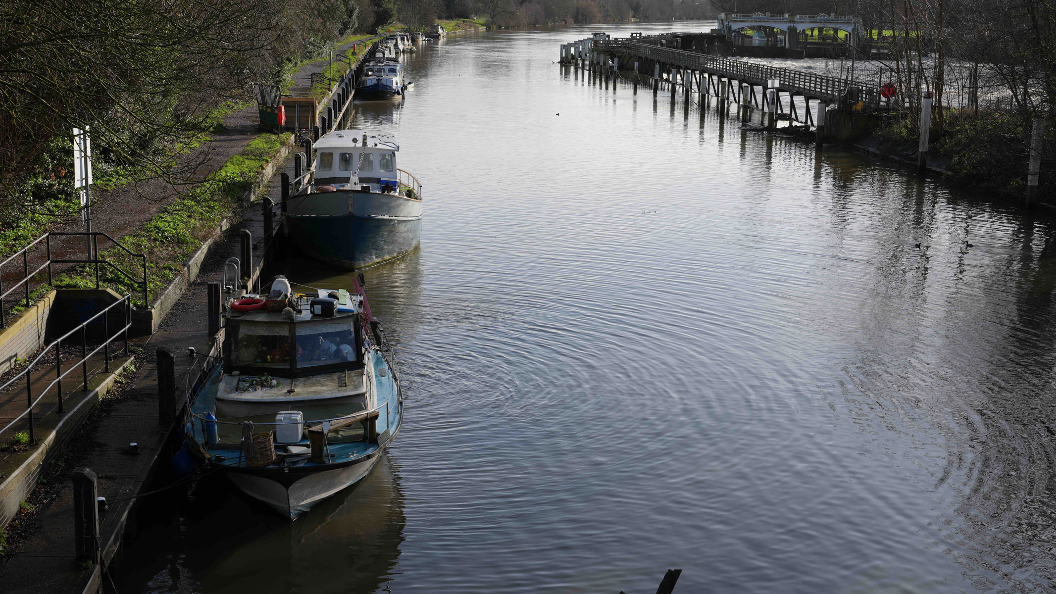A river with boats docked on the left hand side.