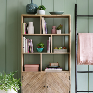 Wood shelving unit that has been organsied. It holds books, houseplants and vases