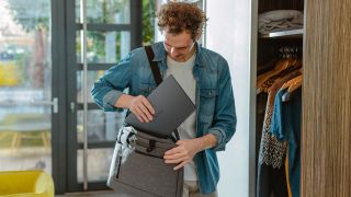 Dell XPS 14 laptop being held by a person putting it into a bag, inside their home
