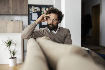 Man thinking on couch at home, deep in contemplation