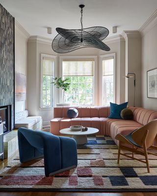 a living room with a pink and blue rug, sofa, and chair