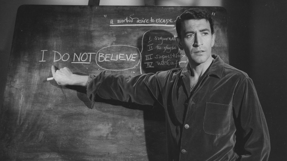 Peter Wyngarde&#039;s Professor points at a blackboard with &quot;I do not believe&quot; written on it.