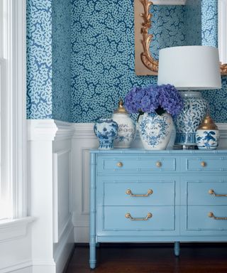 hallway with blue dresser and patterned wallpaper