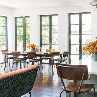 dining area with dining table and glass door with white wall and wooden flooring