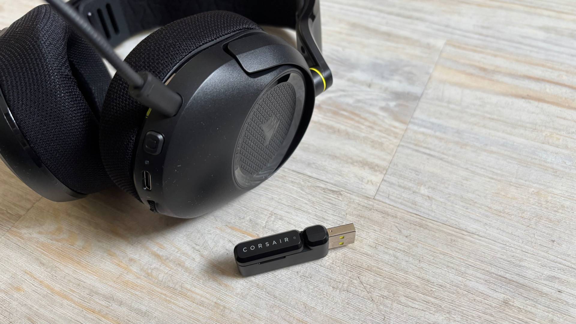 Corsair HS35 v3 headset earcup and dongle and headset on a white hardwood floor