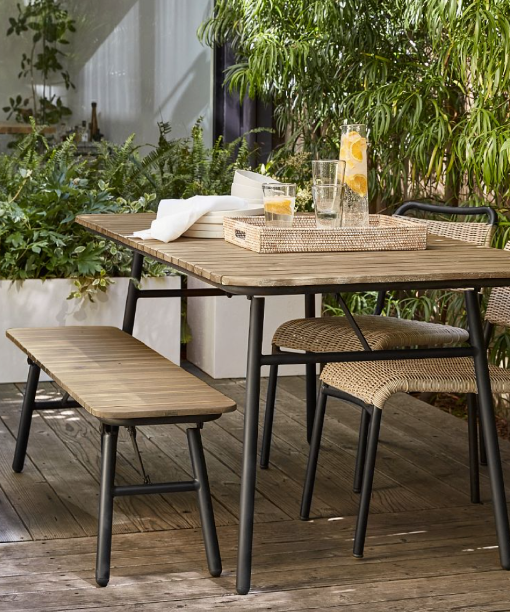 Outdoor table, bench and chairs in wood and black metal with living wall behind