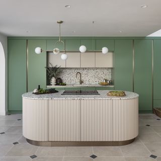 green kitchen with curved pale island with fluting