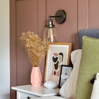 Pink bedroom with glass wall light above bedside table