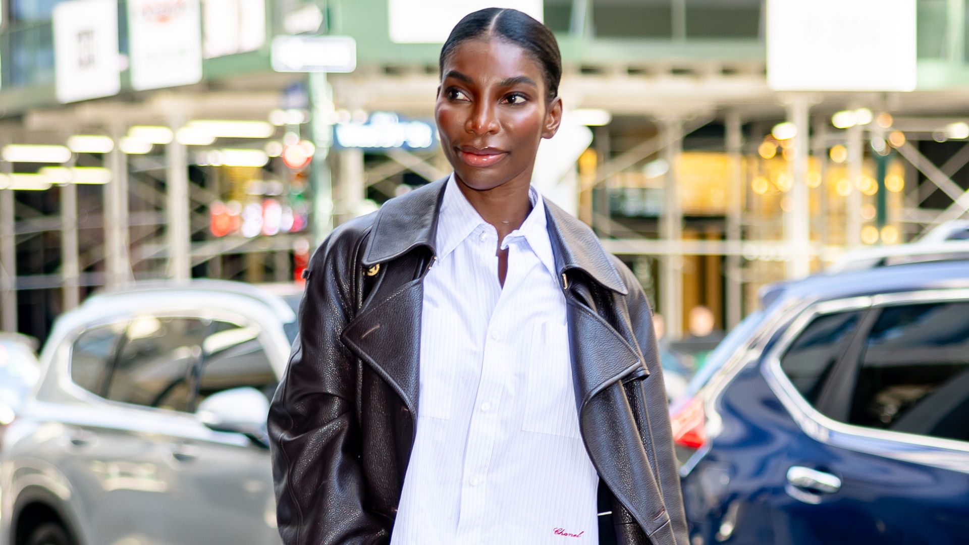 Michaela Coel walks down the street in New York wearing low-rise cuffed jeans with a white shirt, a leather trench coat and Chanel's high-vamp pumps.