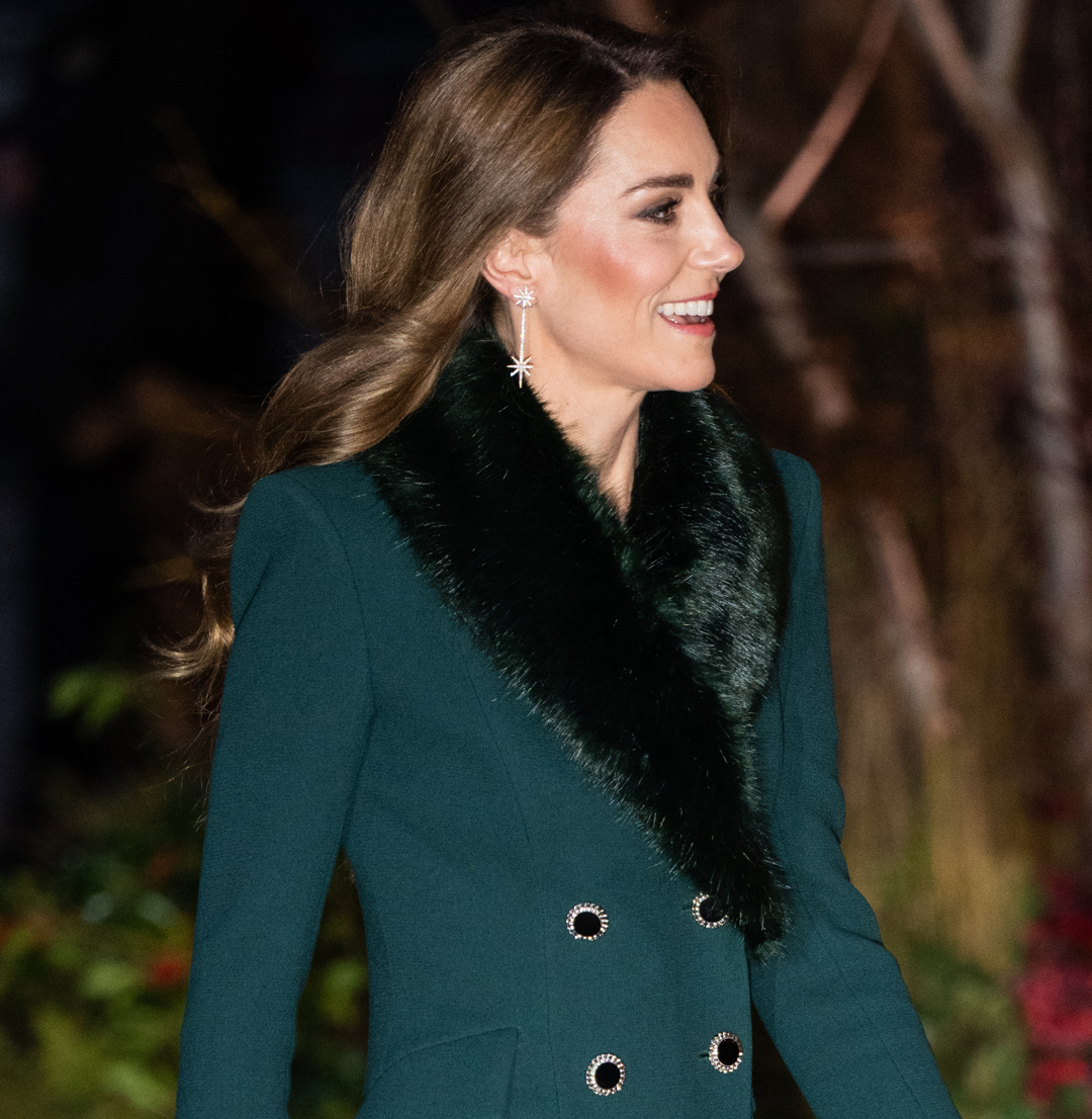 Kate Middleton in a green coat smiling at carol concert