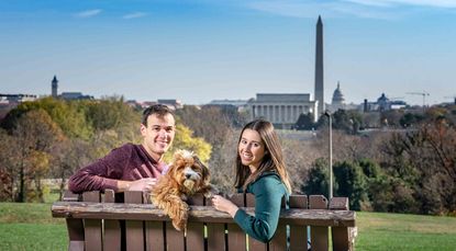 Young couple Daniel Bortz and his wife, Alexandra, sitting on a park bench overlooking Washington, D.C.