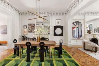 dining room with wood table, black velvet chair, green rug