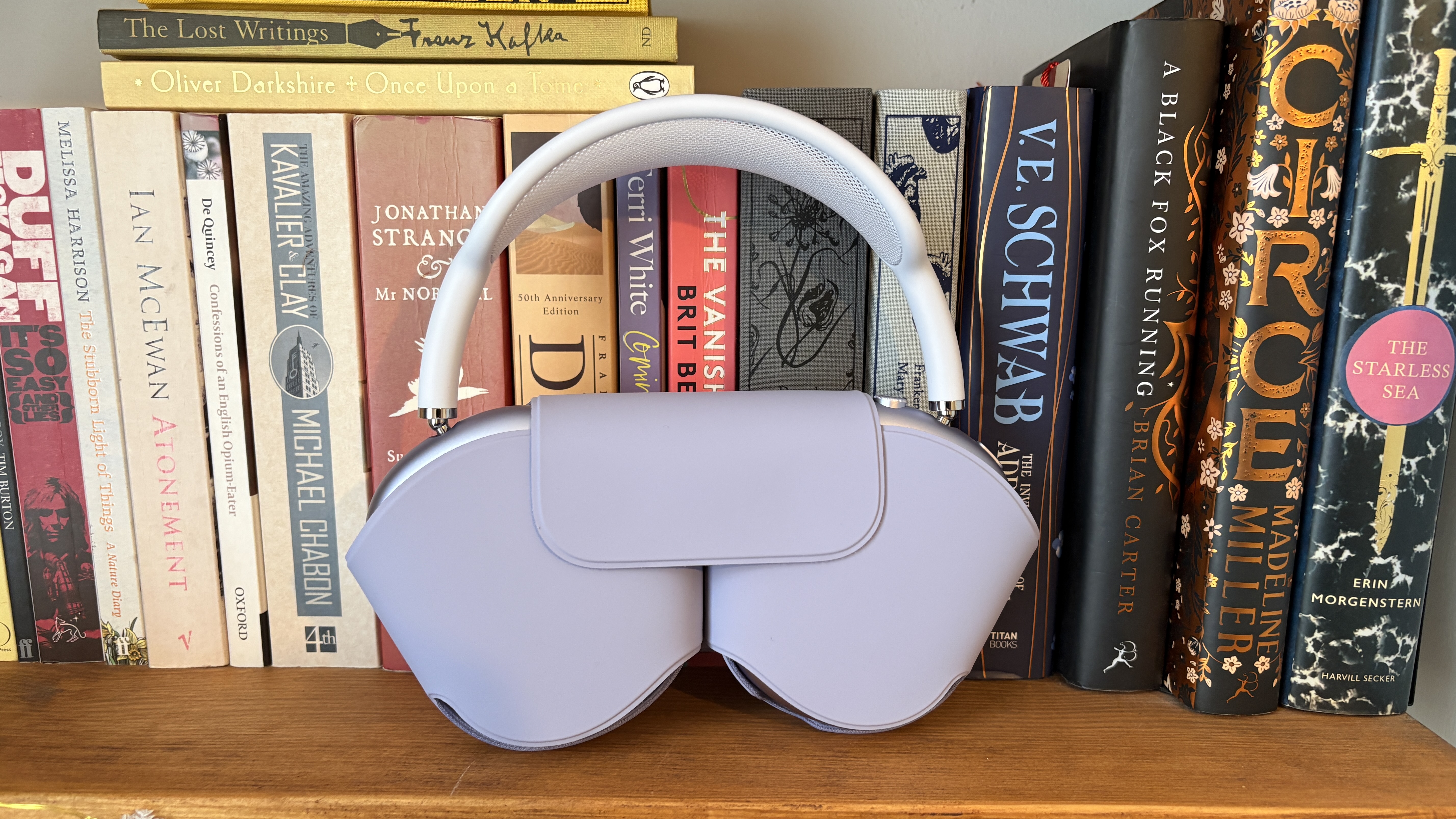 Apple AirPods Max 2 wireless headphones in their case in front of a shelf full of books