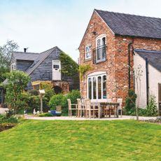 Sloped lawn in garden next to wooden outdoor seating area