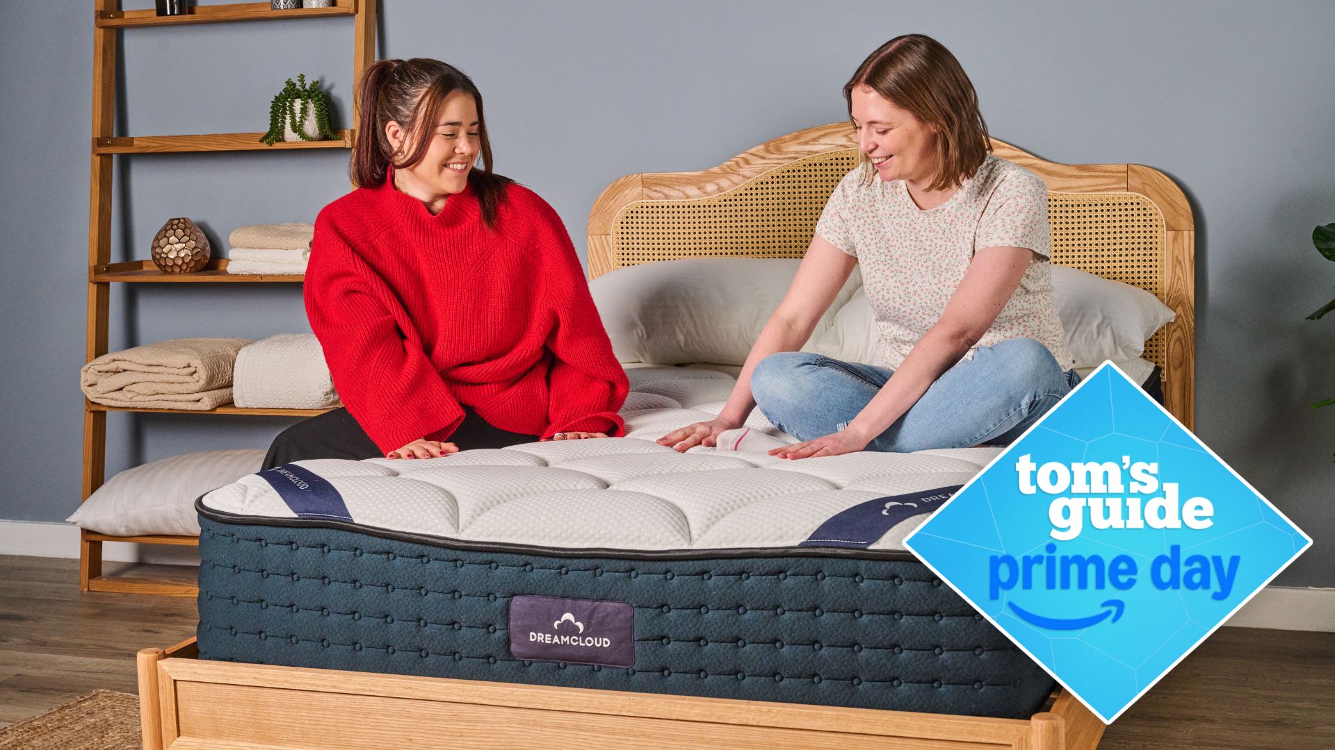 Two girls sitting on navy and white DreamCloud mattress on rattan bedframe in sleep studio