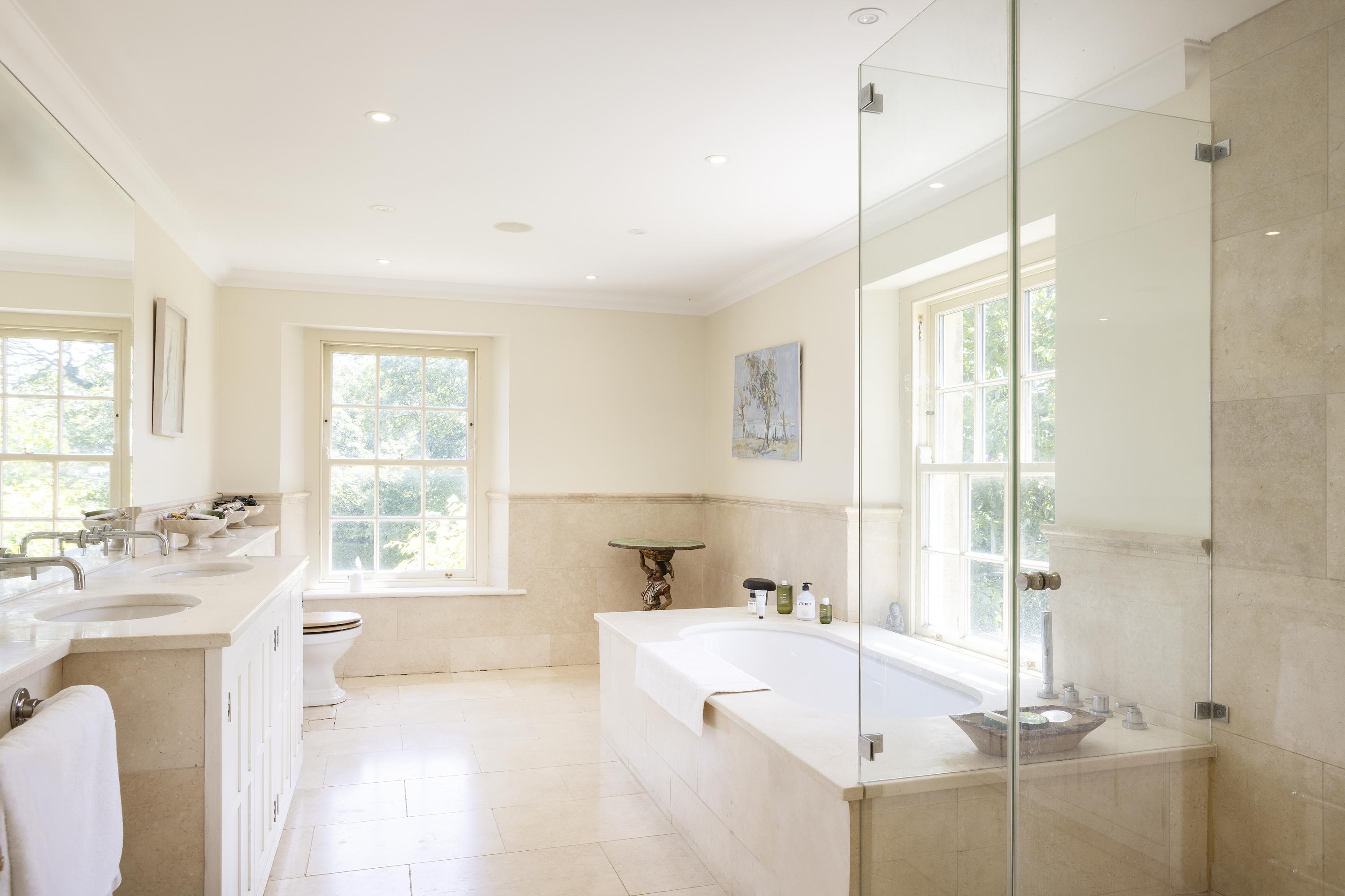A beige bathroom with bath, shower and his and hers sinks inside Mount Farm