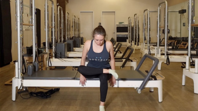 Woman on a Reformer Pilates machine demonstrating an exercise