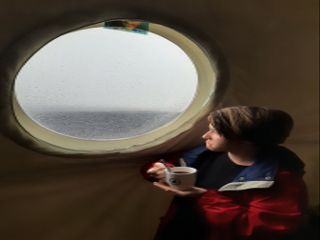 Crew Bioengineer Zoe Maxwell looks out one of the two windows at HI-SEAS in a sad manner, since the view has been that of grey clouds for over a week.