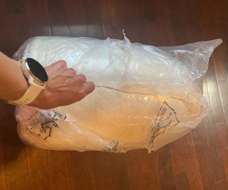 Jamie holding the Nolah Mattress Topper inside the plastic wrap.