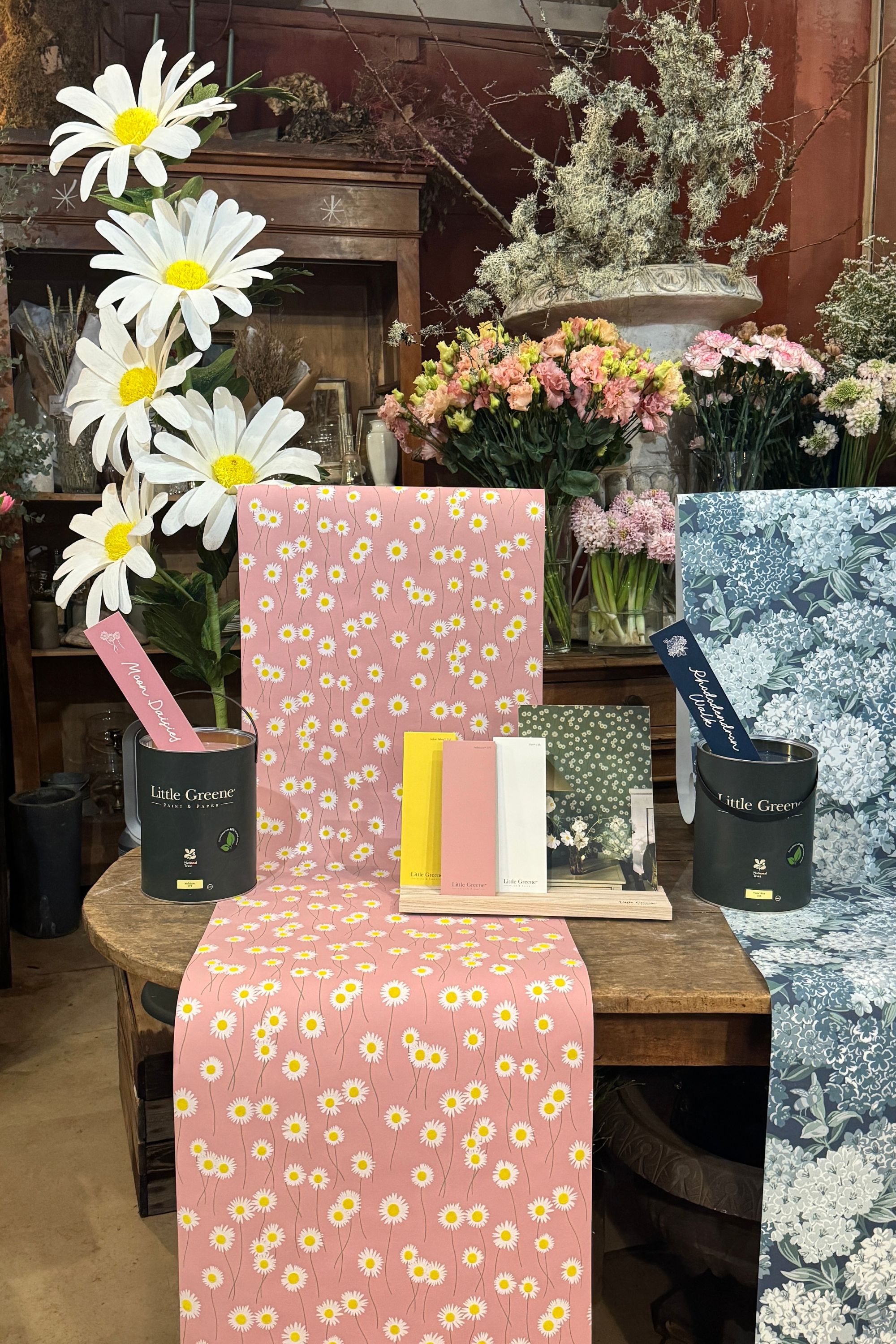 florist with little greene wallpaper with daisies and paint tins with bouquets of flowers in the background
