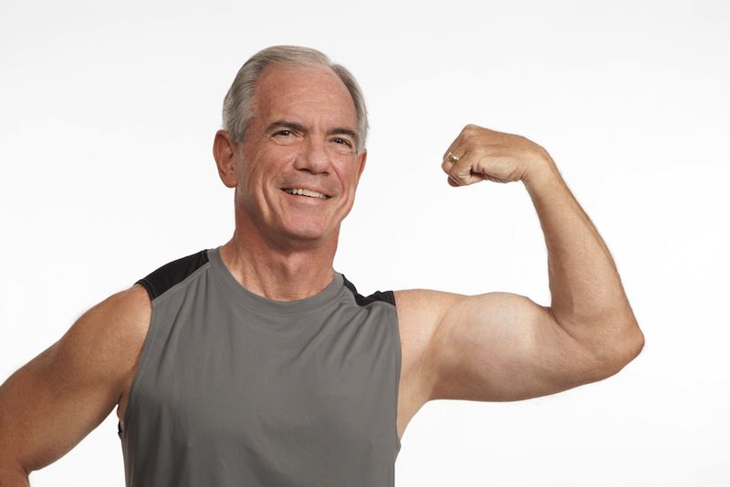 An older man flexes his bicep.