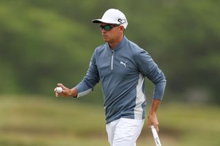 Rickie Fowler waves to the crowd after holing his putt
