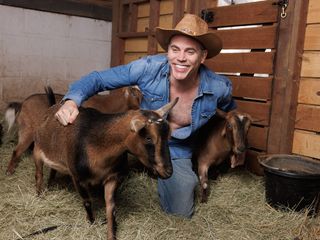 Steve-O hanging out with goats in a blue shirt and cowboy hat