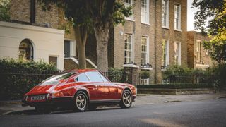A red classic porsche parked on a street with georgian houses in the background