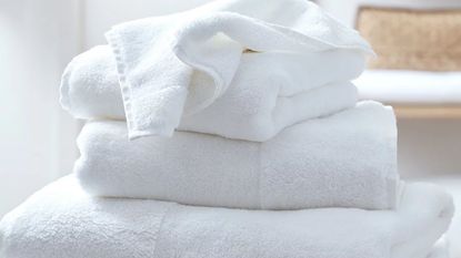Close-up image of a stack of white towels in a white room.
