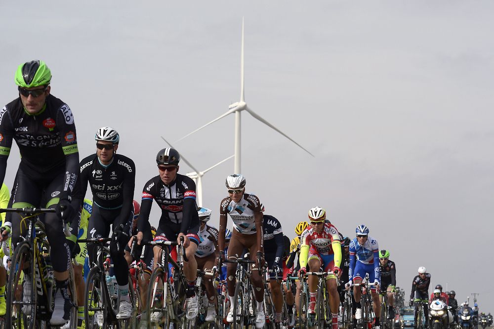France's Romain Bardet (C) rides in the pack past wind turbines during the first stage of the 73rd edition of the Paris-Nice.