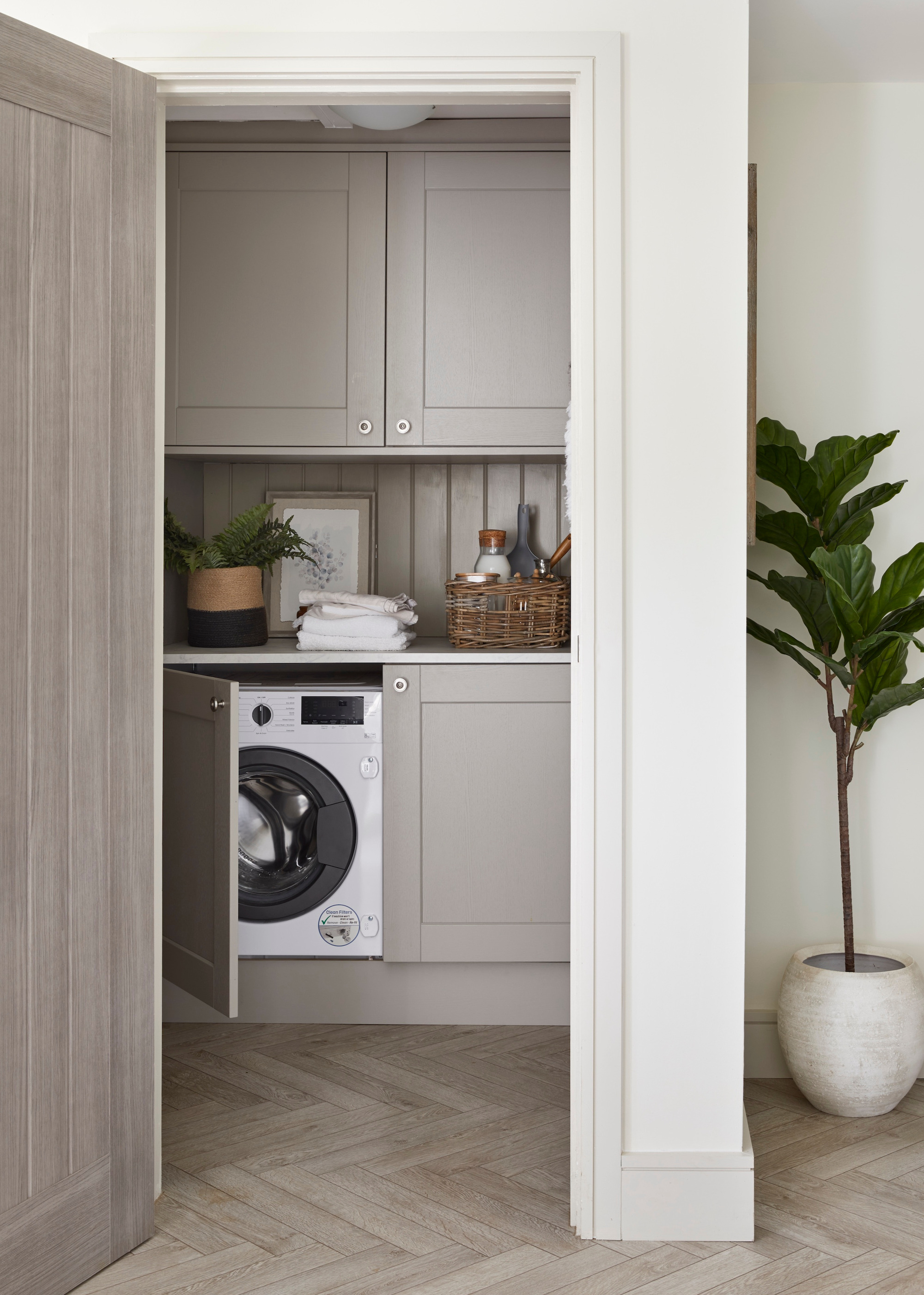 integrated washing machine in taupe utility room with parquet flooring