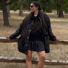 India Cardona wears a navy checked jacket with a pleated skirt and ankle-height boots