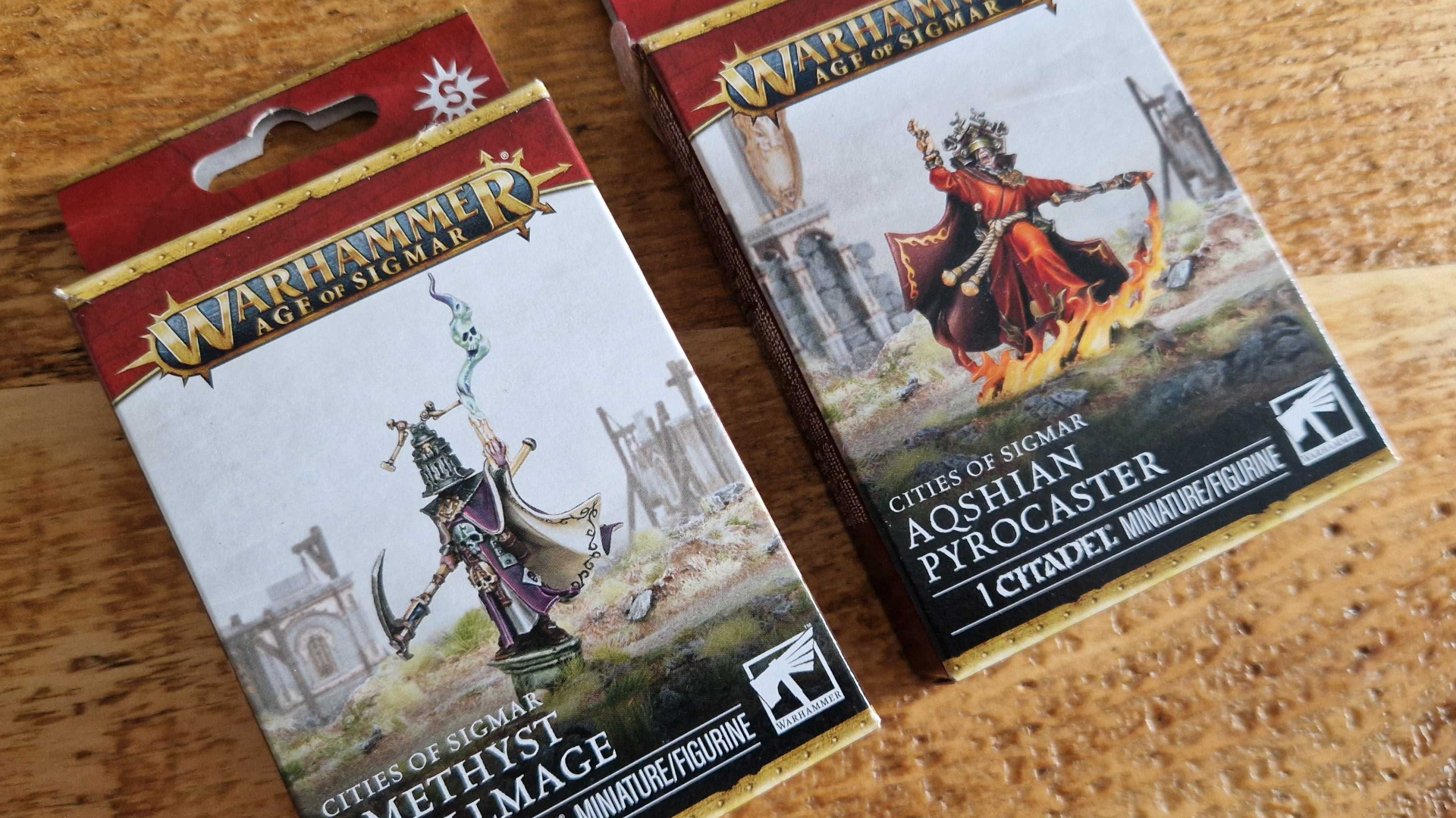 Two Cities of Sigmar wizard model boxes on a wooden table
