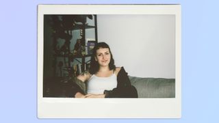 A photo of a woman sitting on a couch, taken on a Fujifilm Instax Wide 400 instant camera