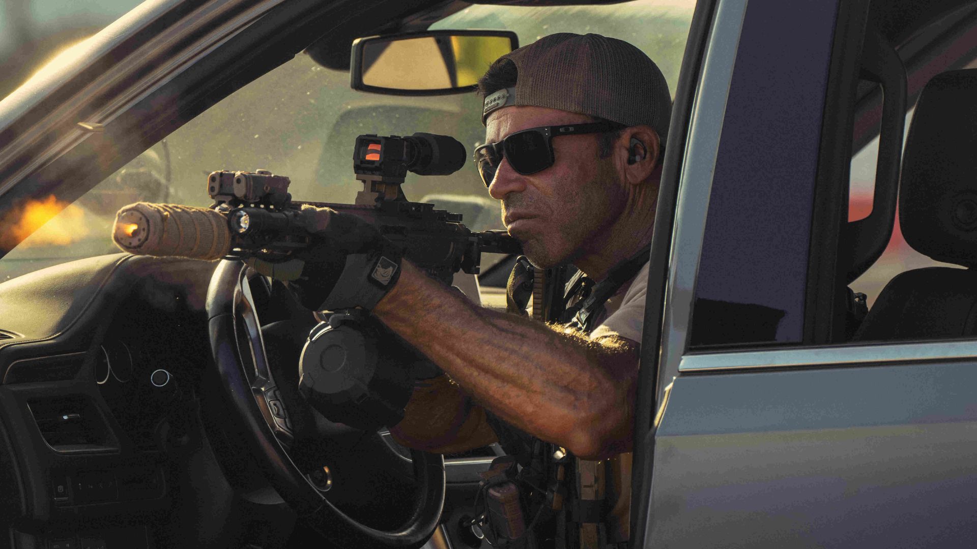 Taylor Sheridan sits in a car pointing a gun