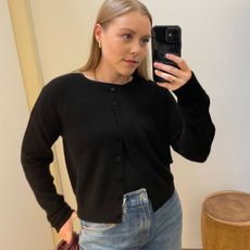 Woman wears black cashmere cardigan and blue jeans