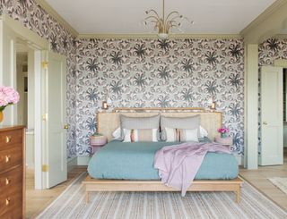 colorful bedroom with statement pattern wallpaper, green woodwork, wooden and rattan bed and blue throw